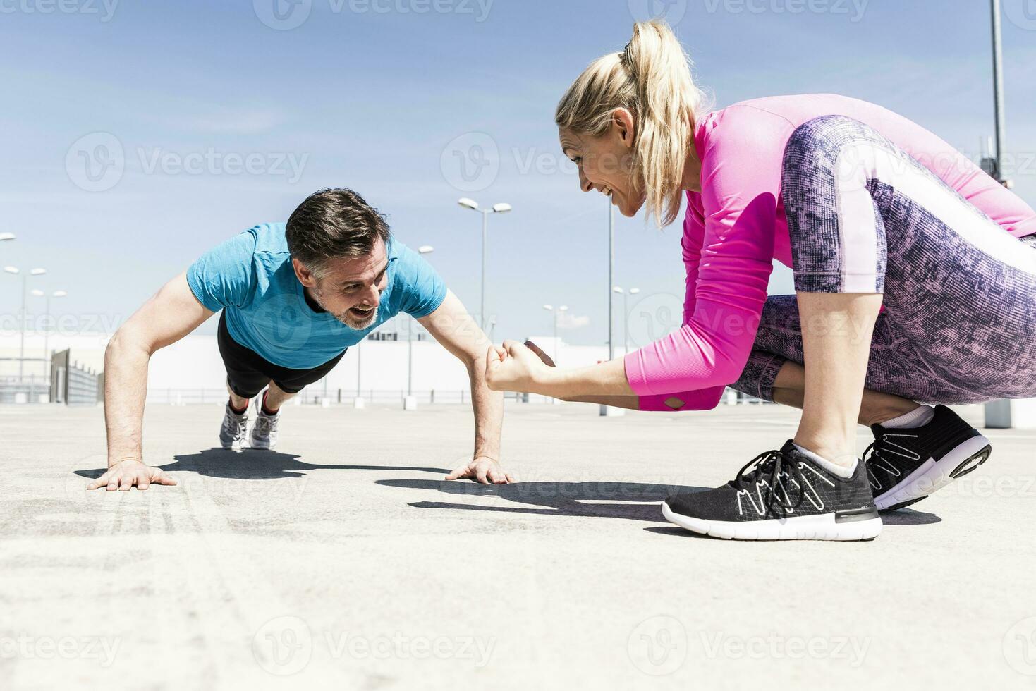 Man exerfining pushups, woman coaching him photo