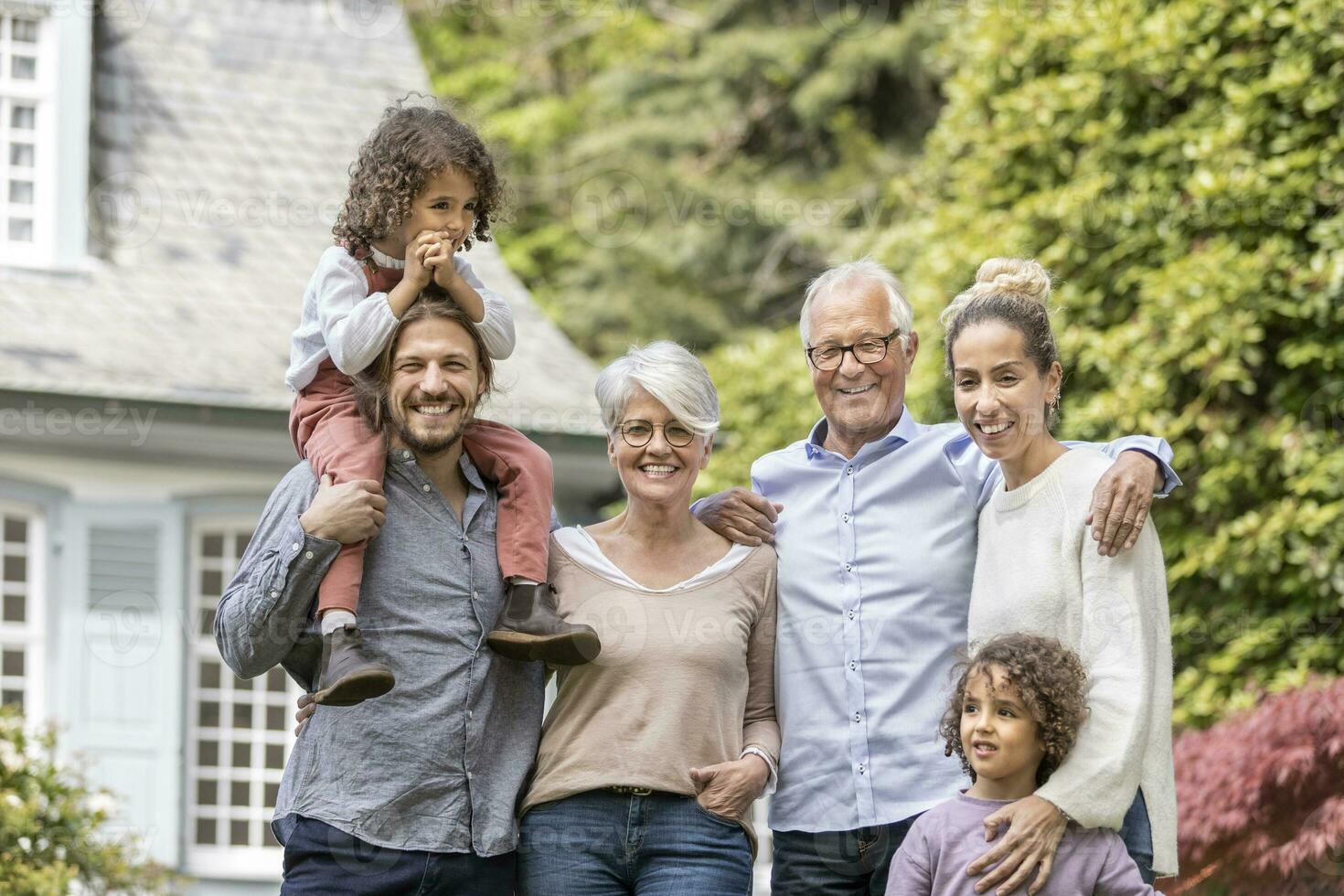 Happy extended family standing in garden of their home photo