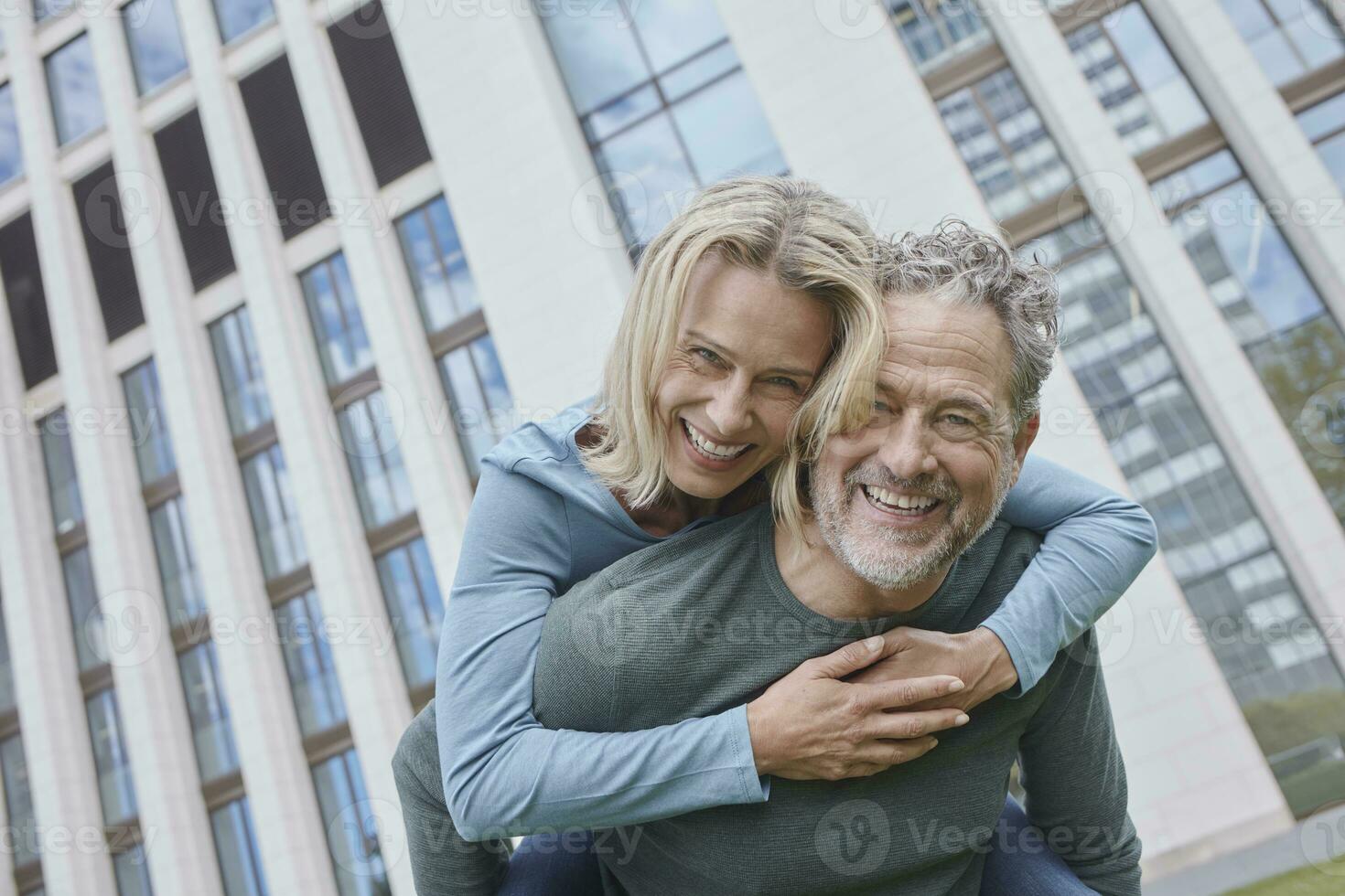 Happy mature man carrying woman piggyback in the city photo
