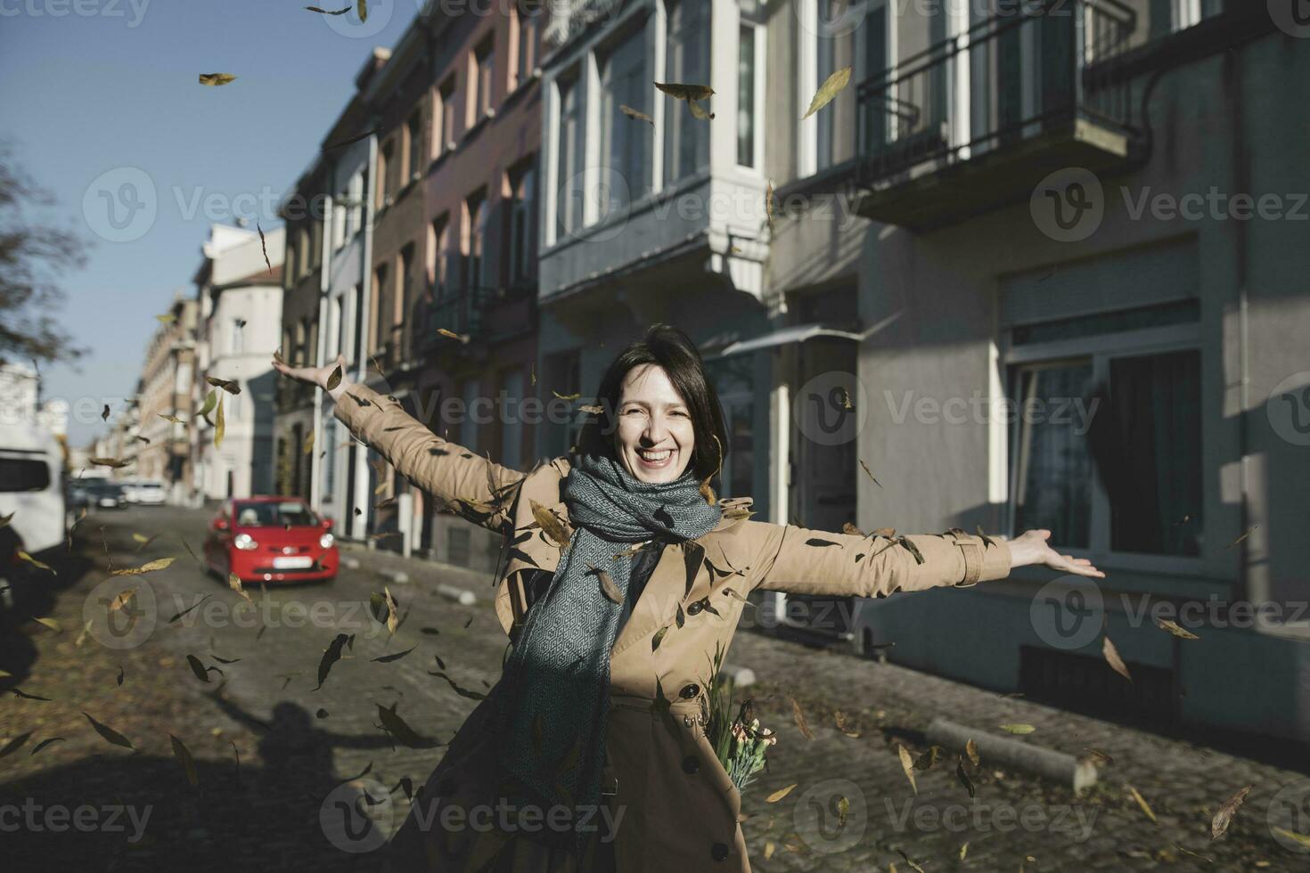 Belgium, Brussels, portrait of happy woman throwing autumn leaves in the air photo