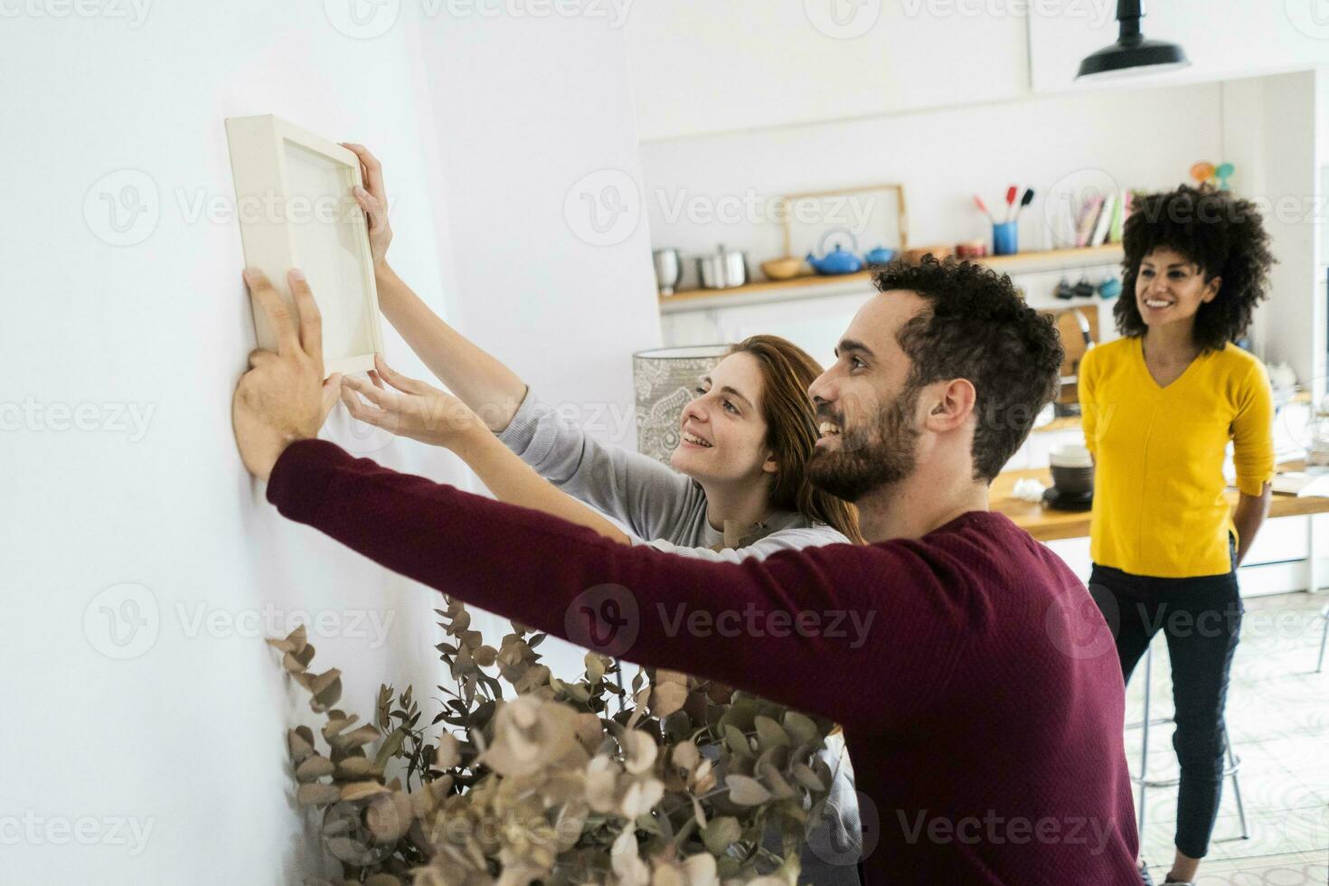 Friends hanging up picture frame at home photo