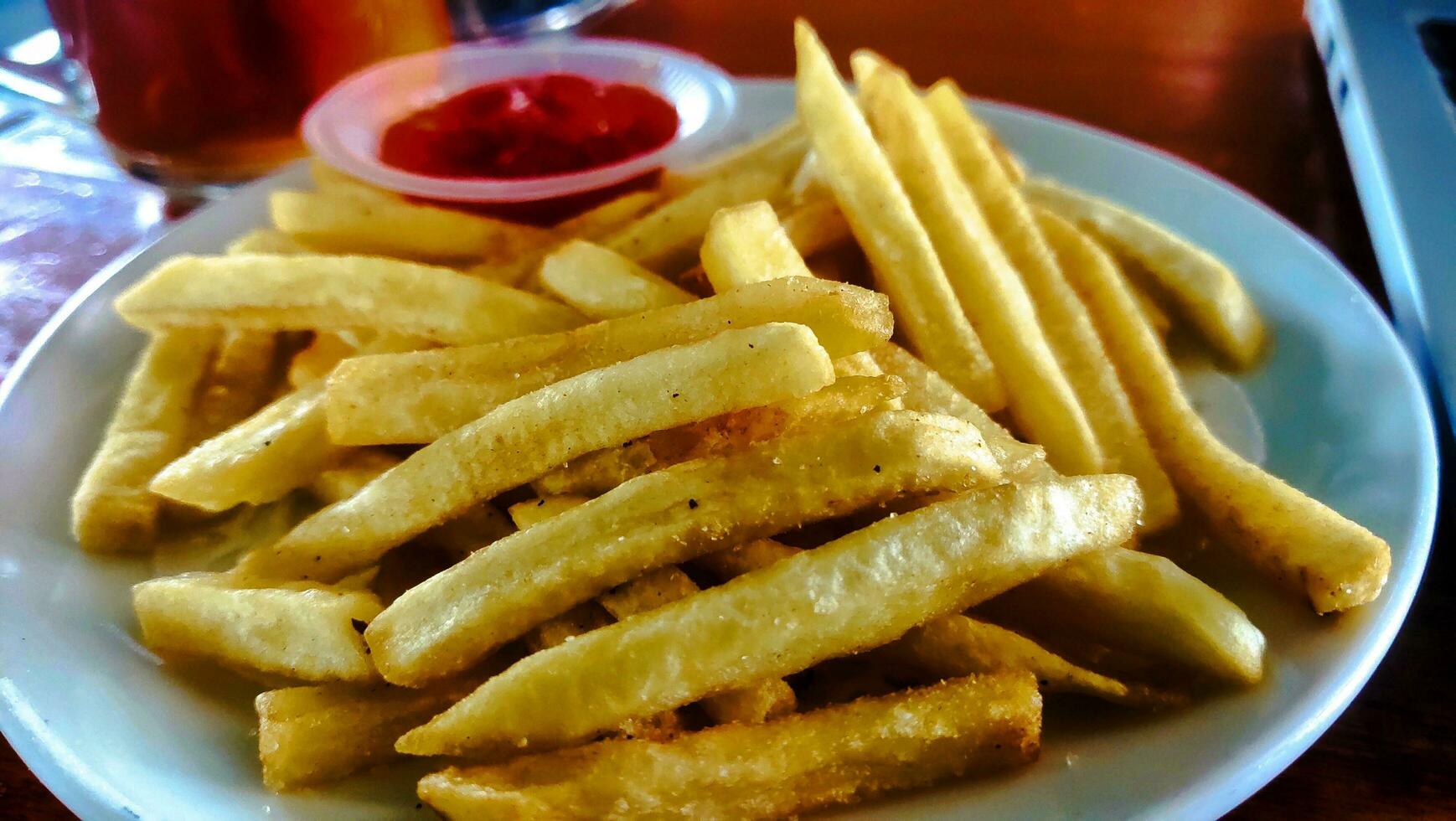 Salted French fries in white plate on a wooden tray photo