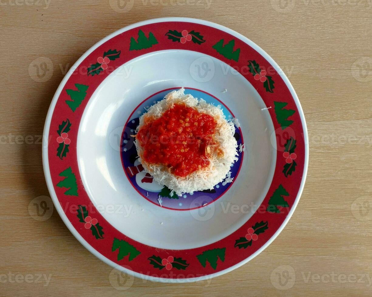 Indonesian food, sticky rice topped with grated coconut and red chili sauce photo