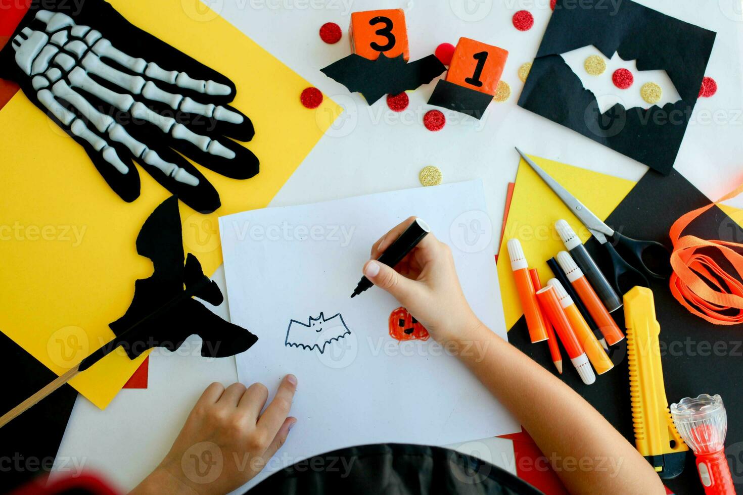 Little girl in a witch costume draw a bat, for the holiday of halloween on a light table. Halloween decor. Handicraft. The concept for Halloween. DIY. photo