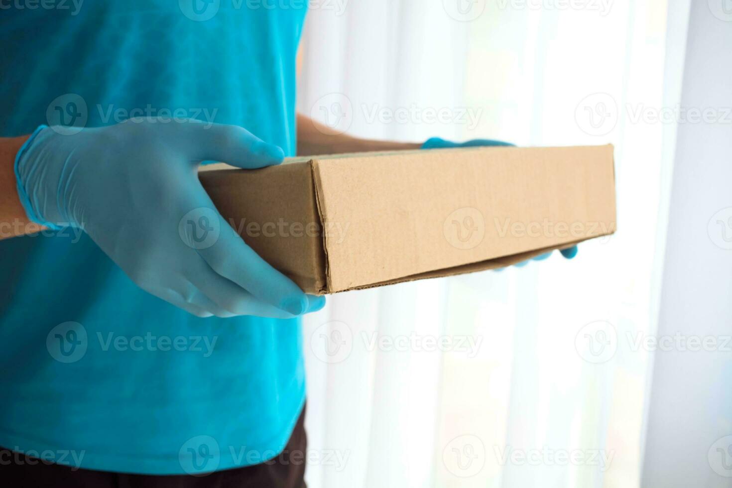 Closeup male hands in blue rubber gloves hold cardboard boxes. Fast and free Delivery transport. Online shopping and Express delivery. photo