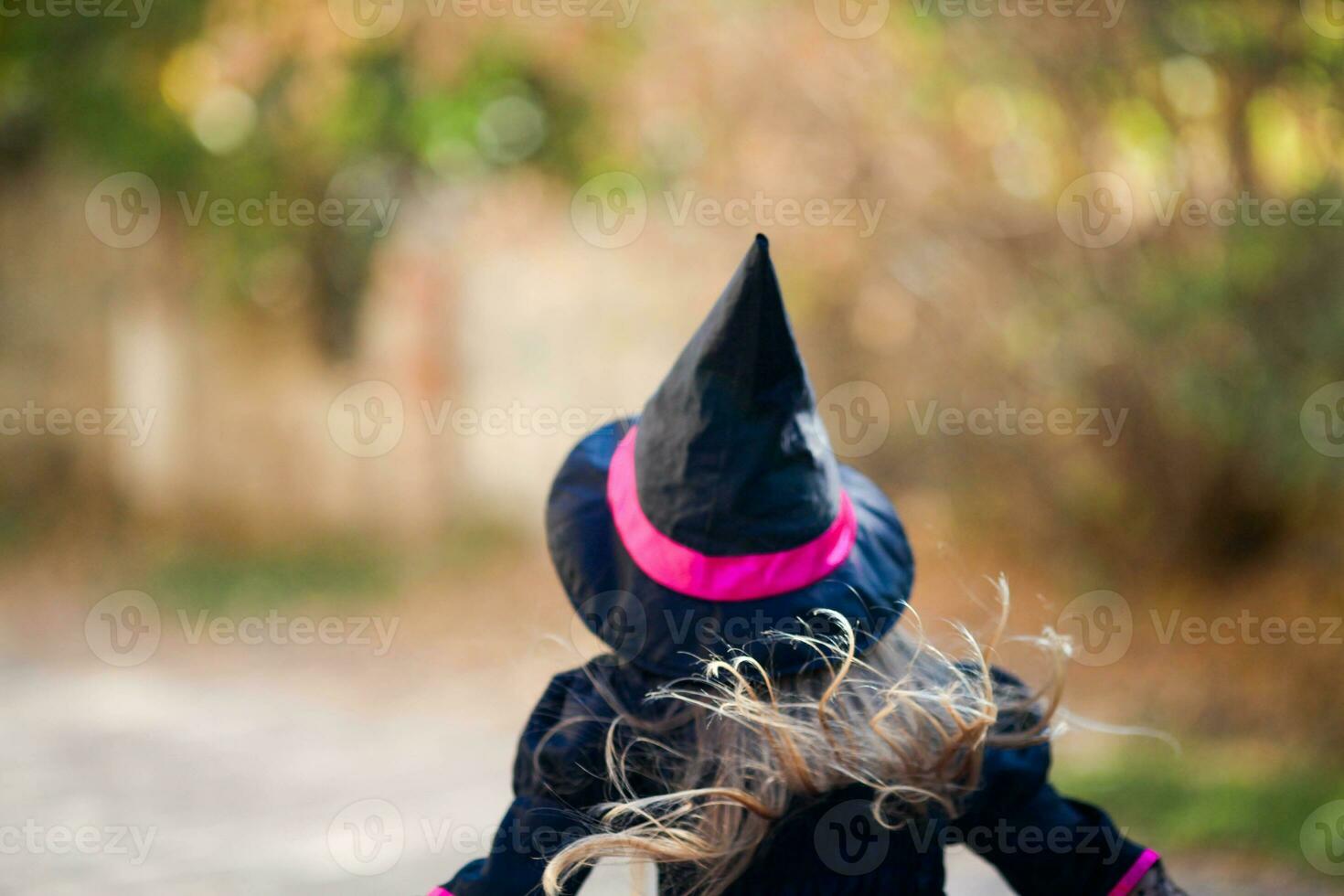 A little girl in a witch costume runs in a black hat. Halloween holiday. photo