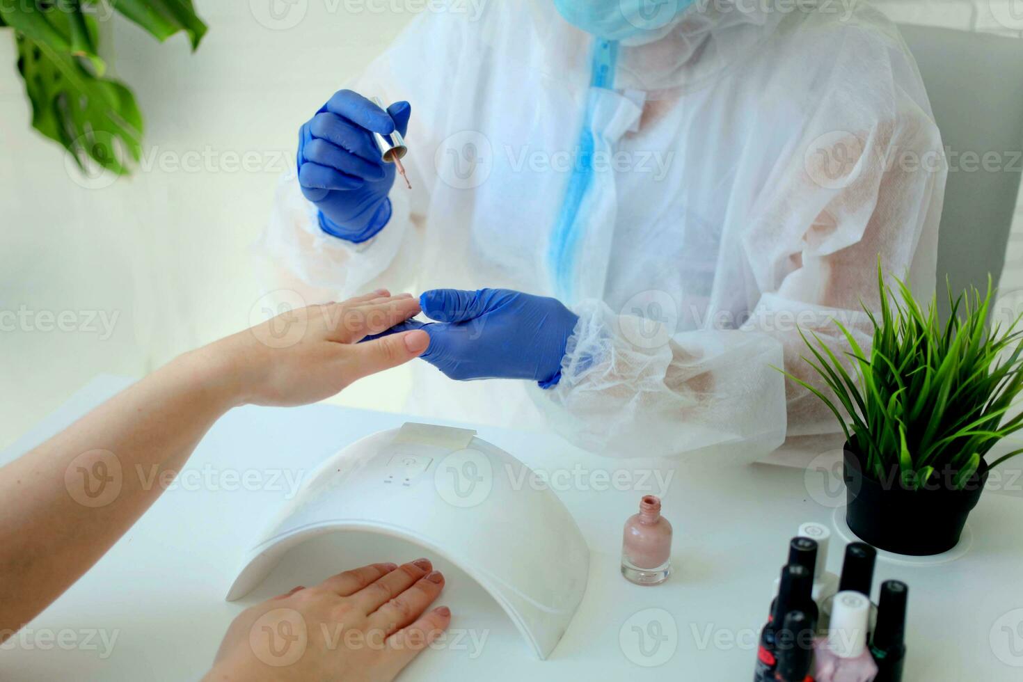 Manicurist in are wearing PPE paints nails in a beauty salon. . The existence of small businesses in isolation from COVID-19. photo