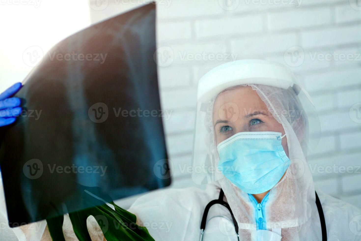 The doctor in PPE looks thoughtfully at the X-ray. photo