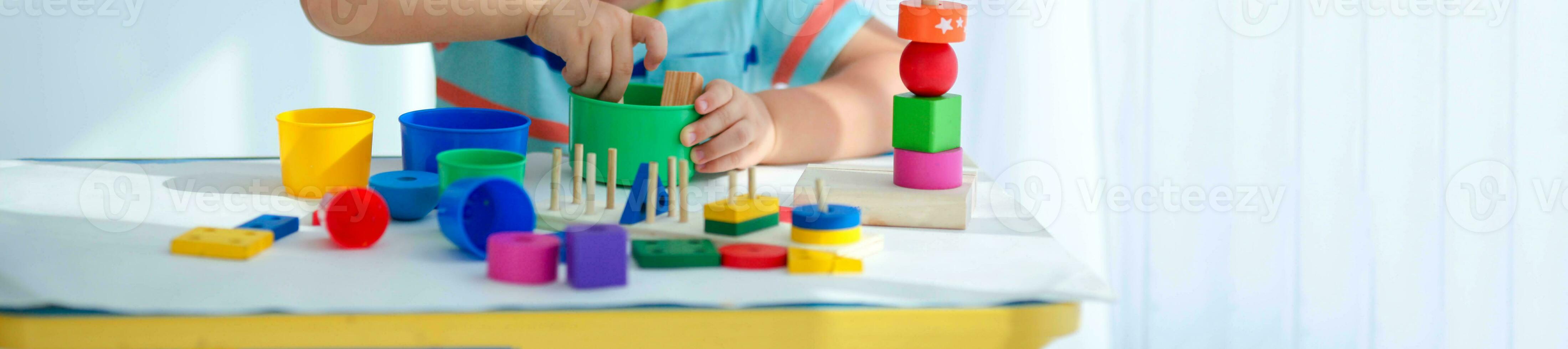 Close-up of a little boy is hand is played with wooden toys. Educational logic toys for children. Montessori games for child development. Copy space. photo