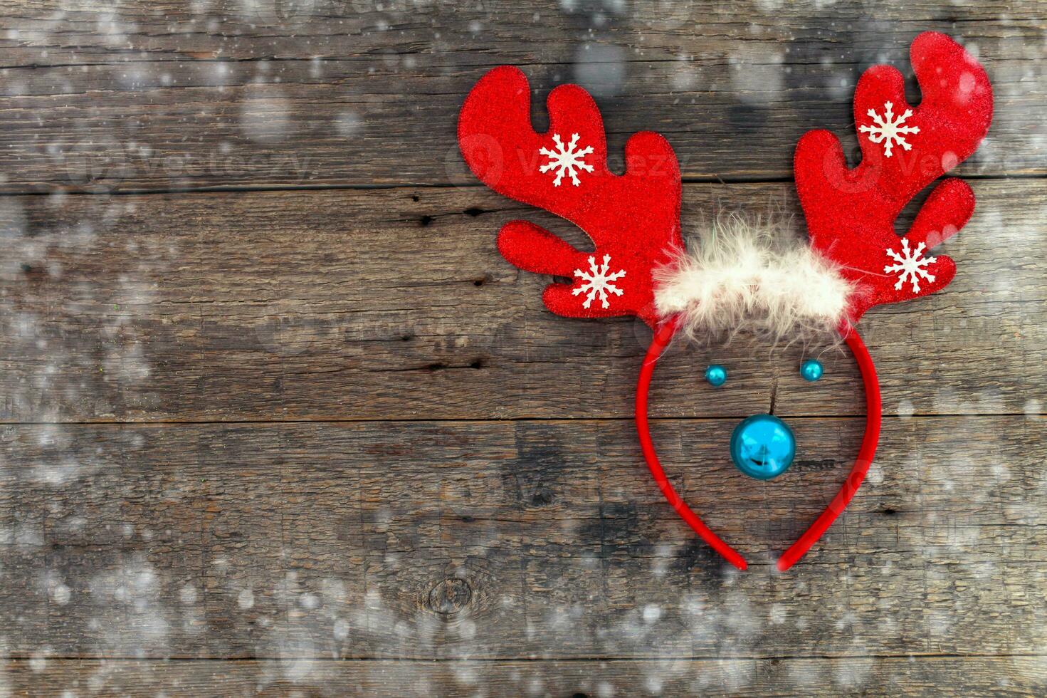 Christmas reindeer concept made from hoop with deer antlers, red decoration toy on wooden background. Copy space. photo