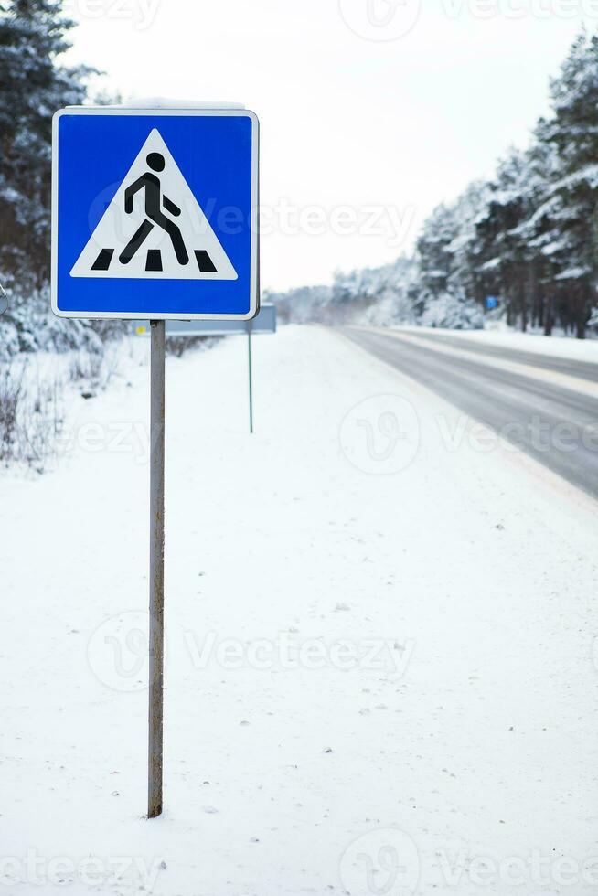 Beautiful winter road in the middle of the forest with signs and zebra crossing, pedestrian crossing. photo