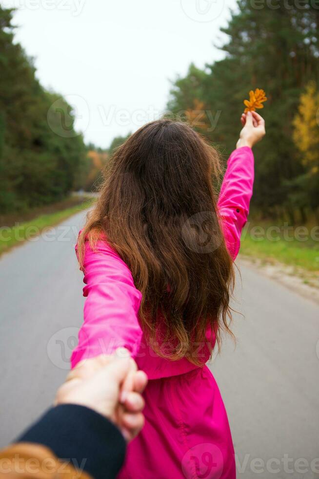 the girl is standing on the road holding a yellow leaf photo