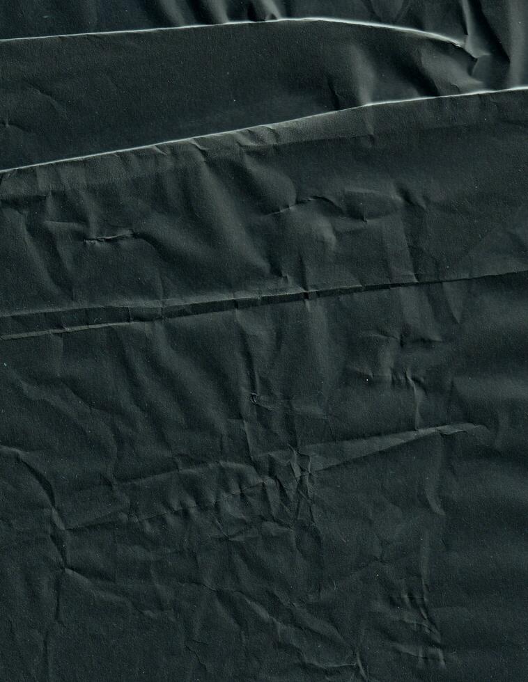 Creased black paper texture background. Crumpled and wrinkled grunge backdrop. photo