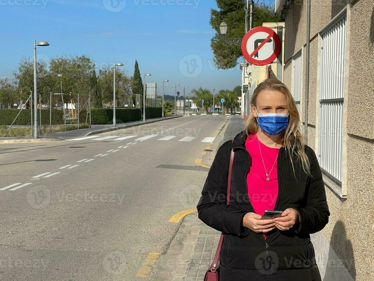 Alone in empty street. Urban portrait of a woman in mask photo