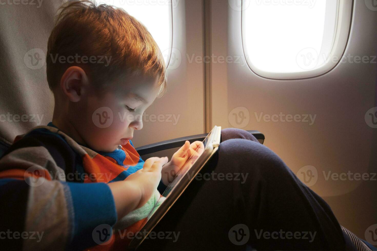 Child using tablet computer during flight photo