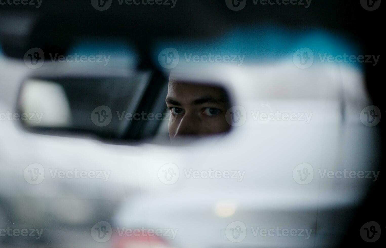 Man looking in the rear view mirror while driving photo