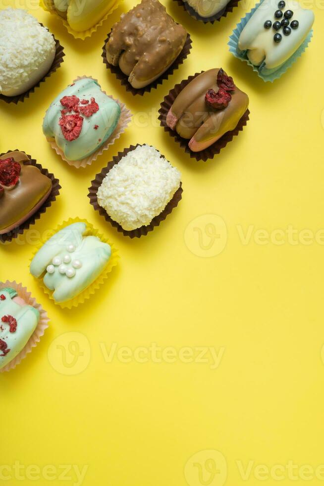 Set of different macaroons on yellow background top view, flat lay. Copy space. photo