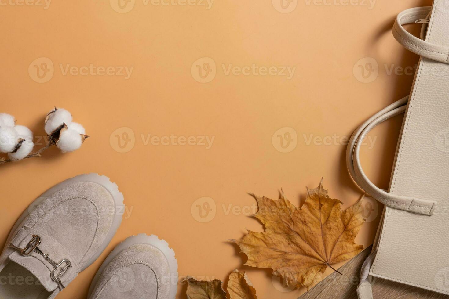 Woman's shoes, bag with autumn leaves on orange background with copy space top view, flat lay photo