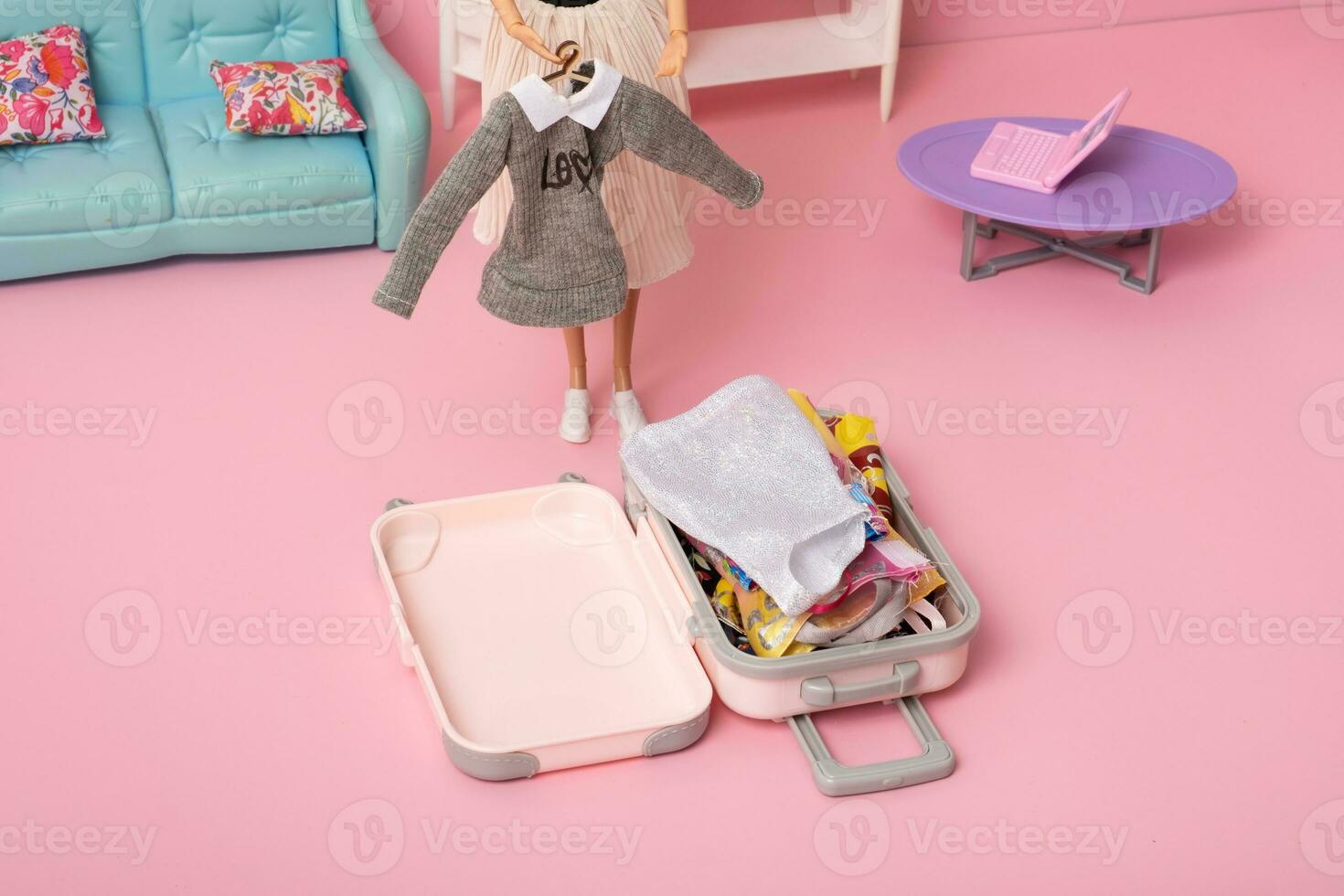 The doll puts clothes in a suitcase. Travel concept. Doll world. photo