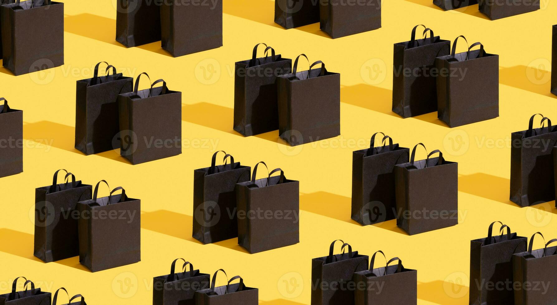 Pttetn made from black paper shopping bags on yellow background. Black friday sale, shopping concept. Banner. photo