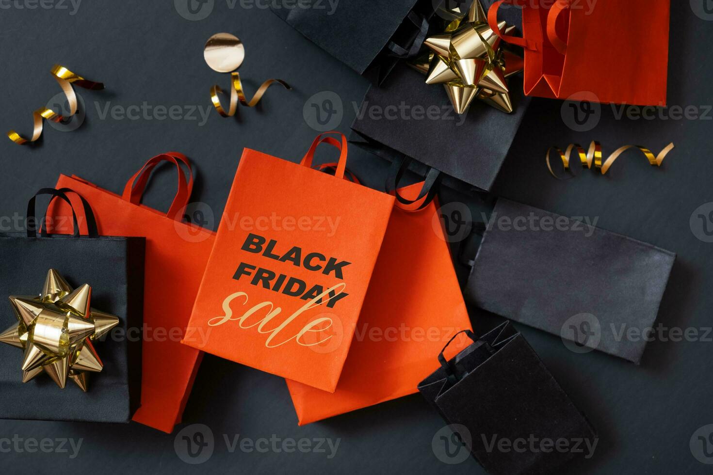 Black friday sale text, shopping concept. Red and black paper shopping bags with decorations on black background. photo