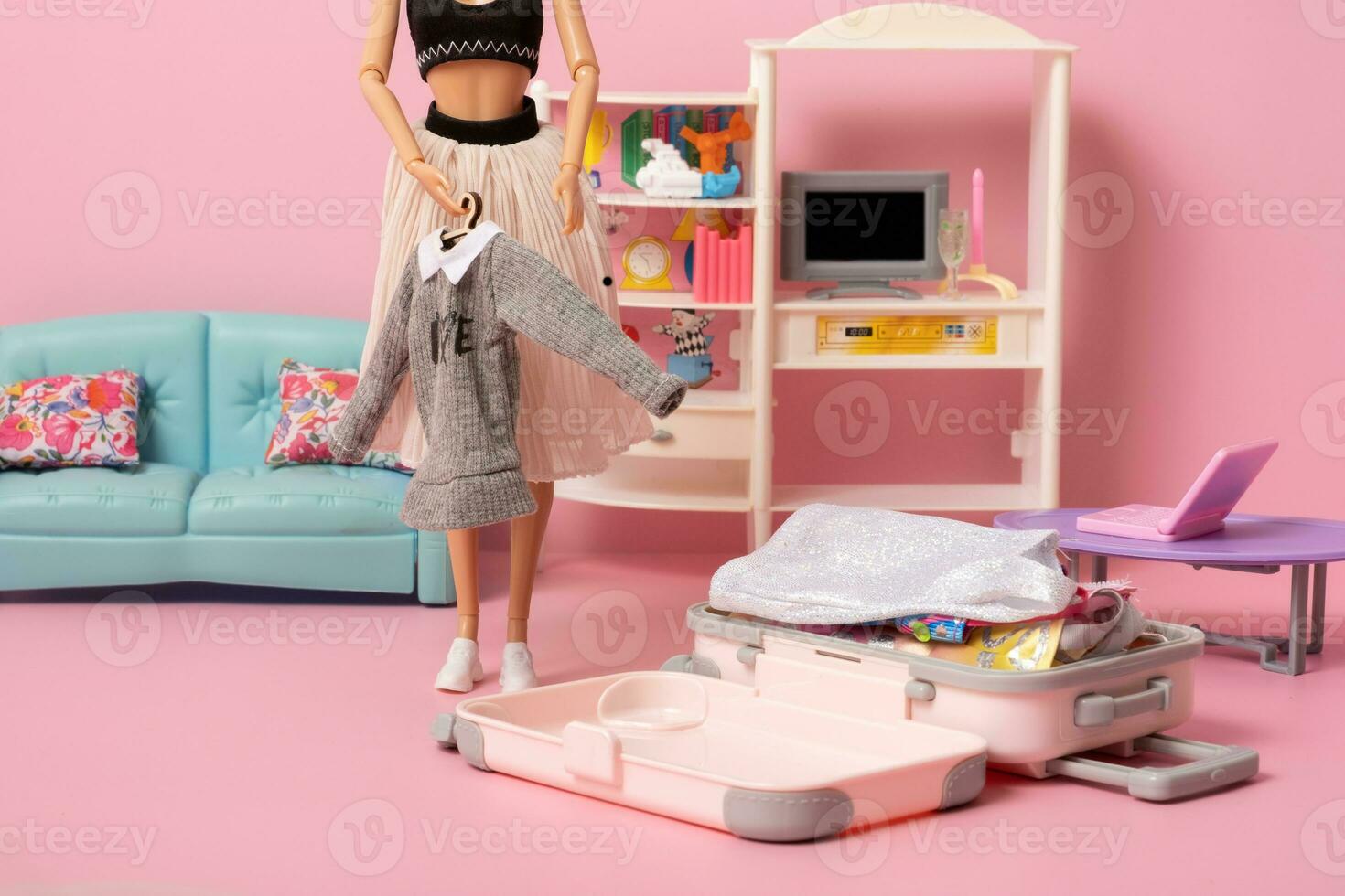 The doll puts clothes in a baggage. Creative travel and vacation concept photo