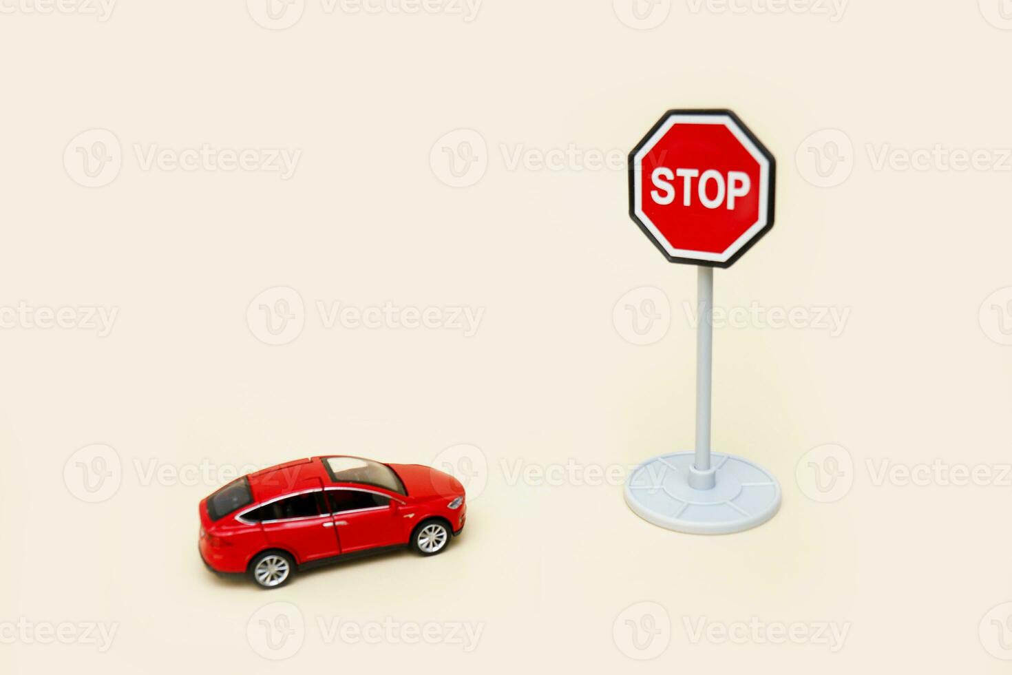 juguete rojo coche en frente de un detener firmar en un ligero antecedentes con Copiar espacio foto