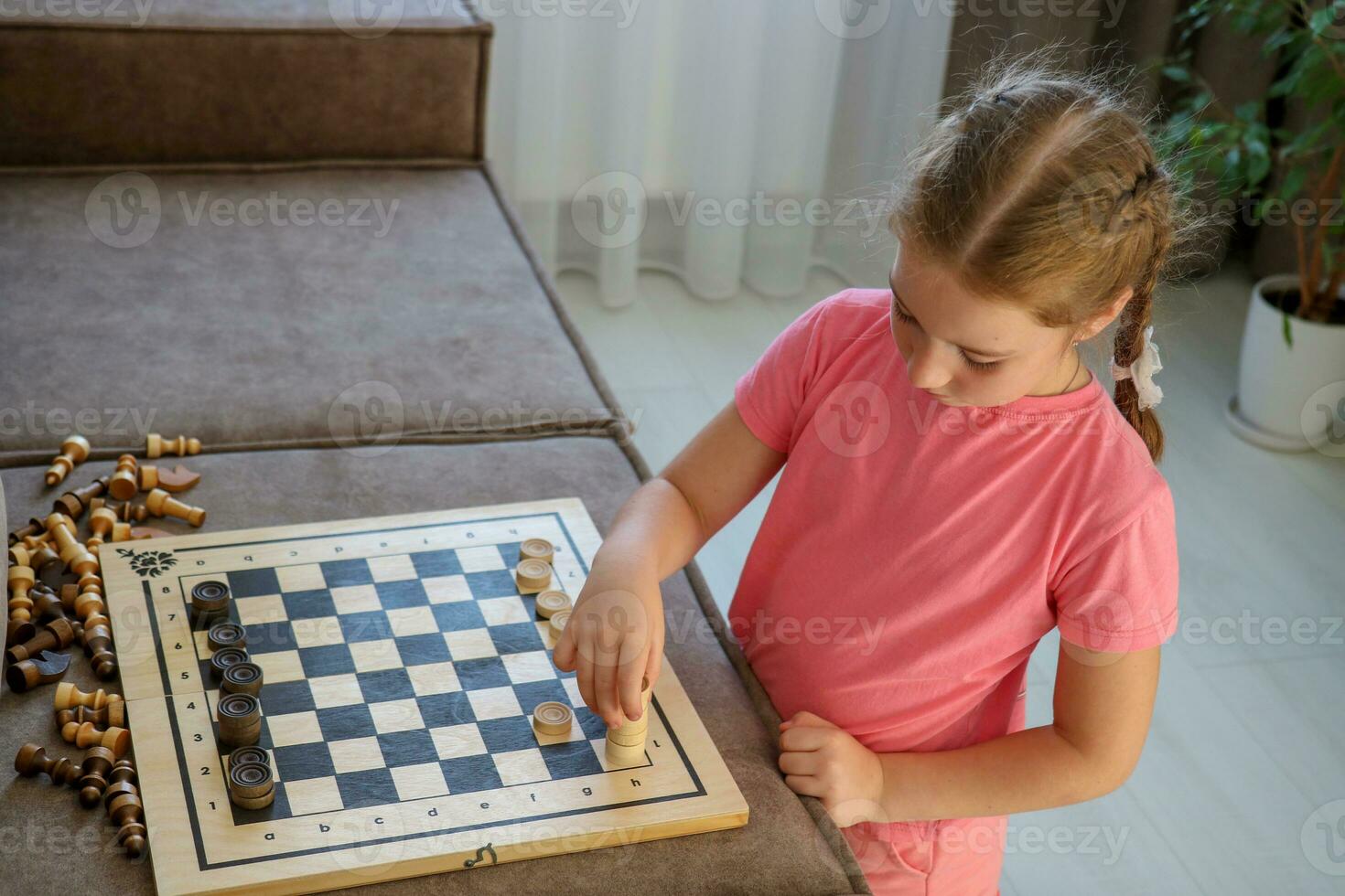 girl plays an invented game at home with a chessboard, checkers and chess photo