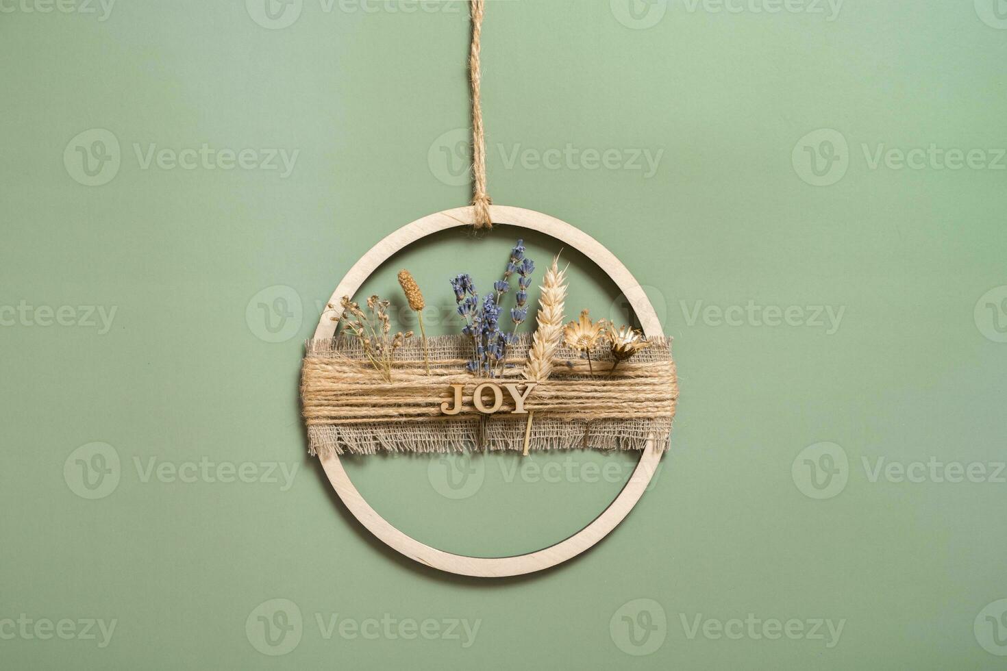 Handmade home decor from a wooden circle and dried flowers with the inscription Joy photo