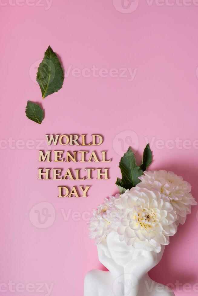 World Mental Health Day with figurine of head with flowers on a pink background. photo
