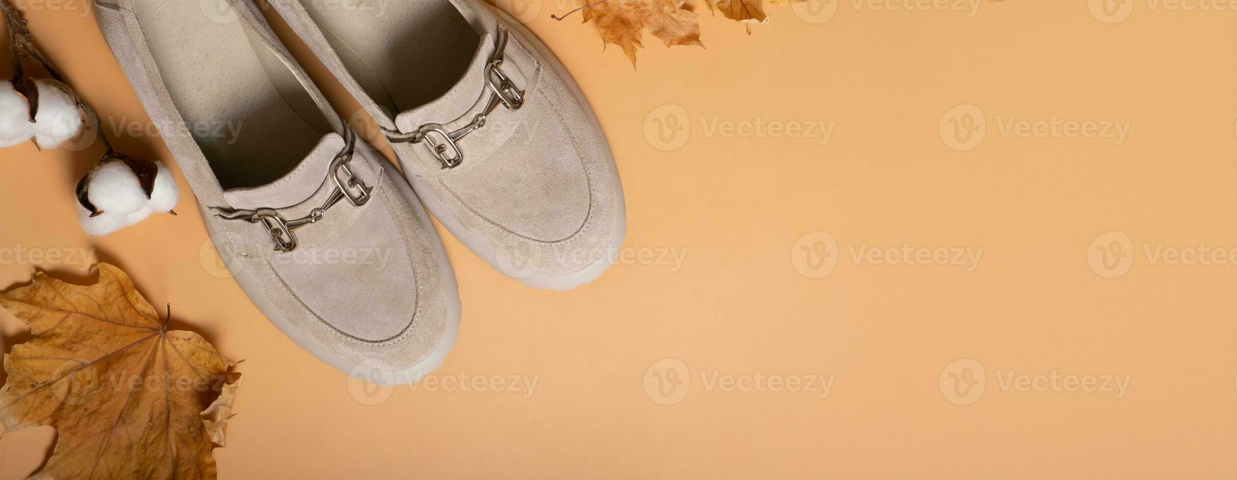 Suede shoes with autumn leaves and cotton candy on orange background top view. Casual fashion flat lay with copy space. photo