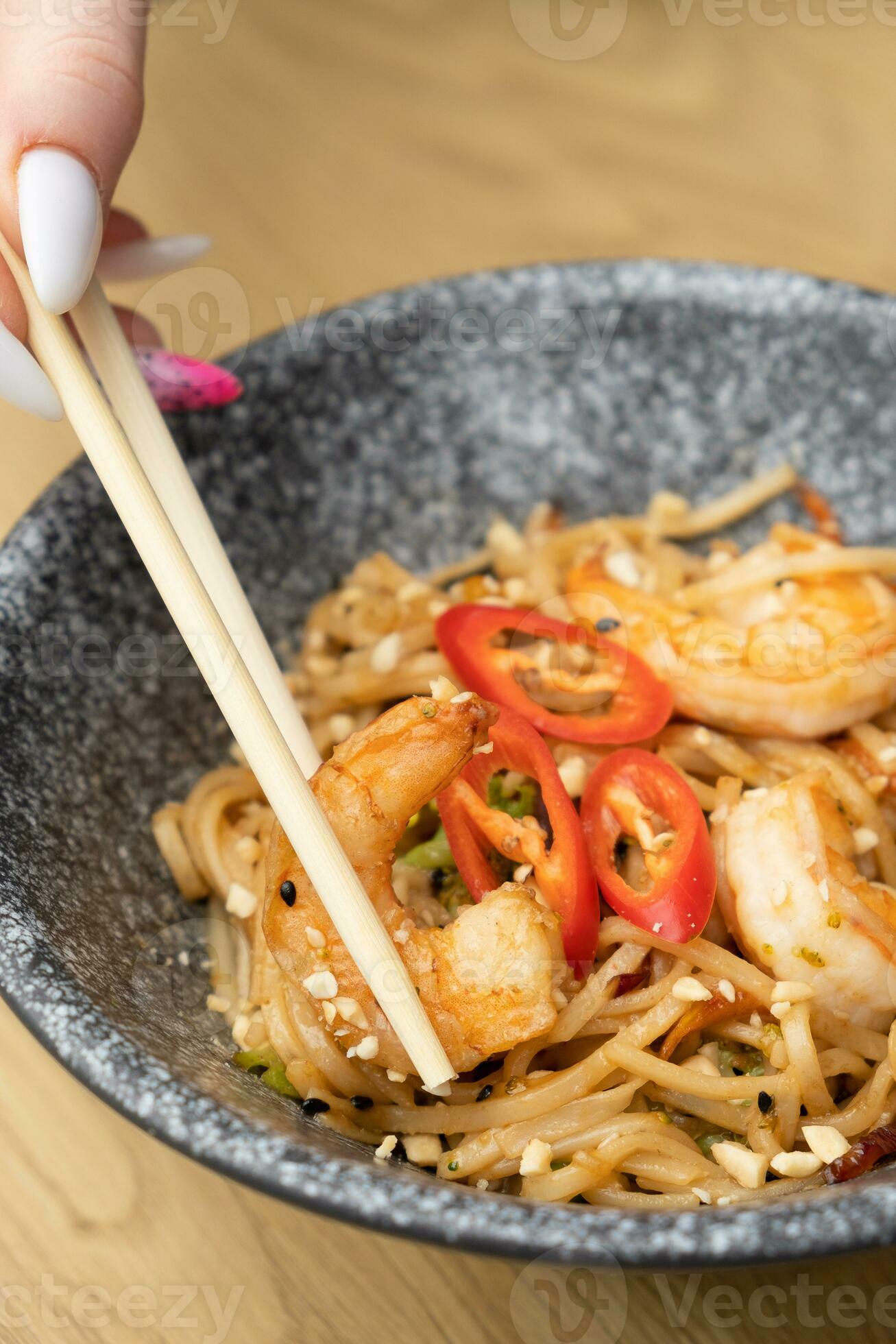 Close up udon noodles with shrimp and fried vegetables in a bowl top