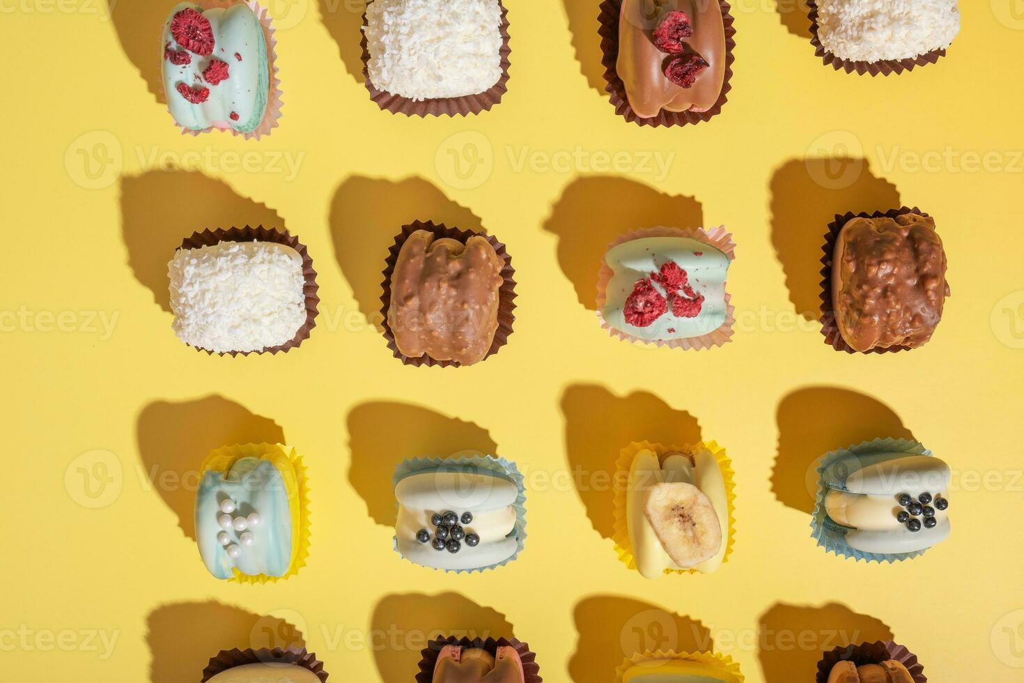 Set of different beautiful macaroons on yellow background top view, flat lay photo