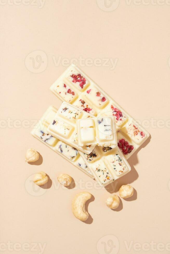 Craft white chocolates candies with nuts on beige background flat lay, top view photo