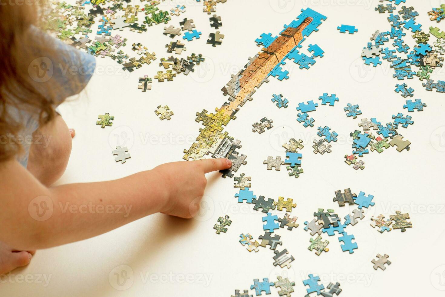 girl collects a puzzle from small pieces photo