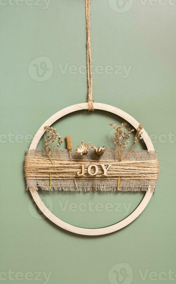 Handmade home decor from a wooden circle and dried flowers with the inscription Joy photo