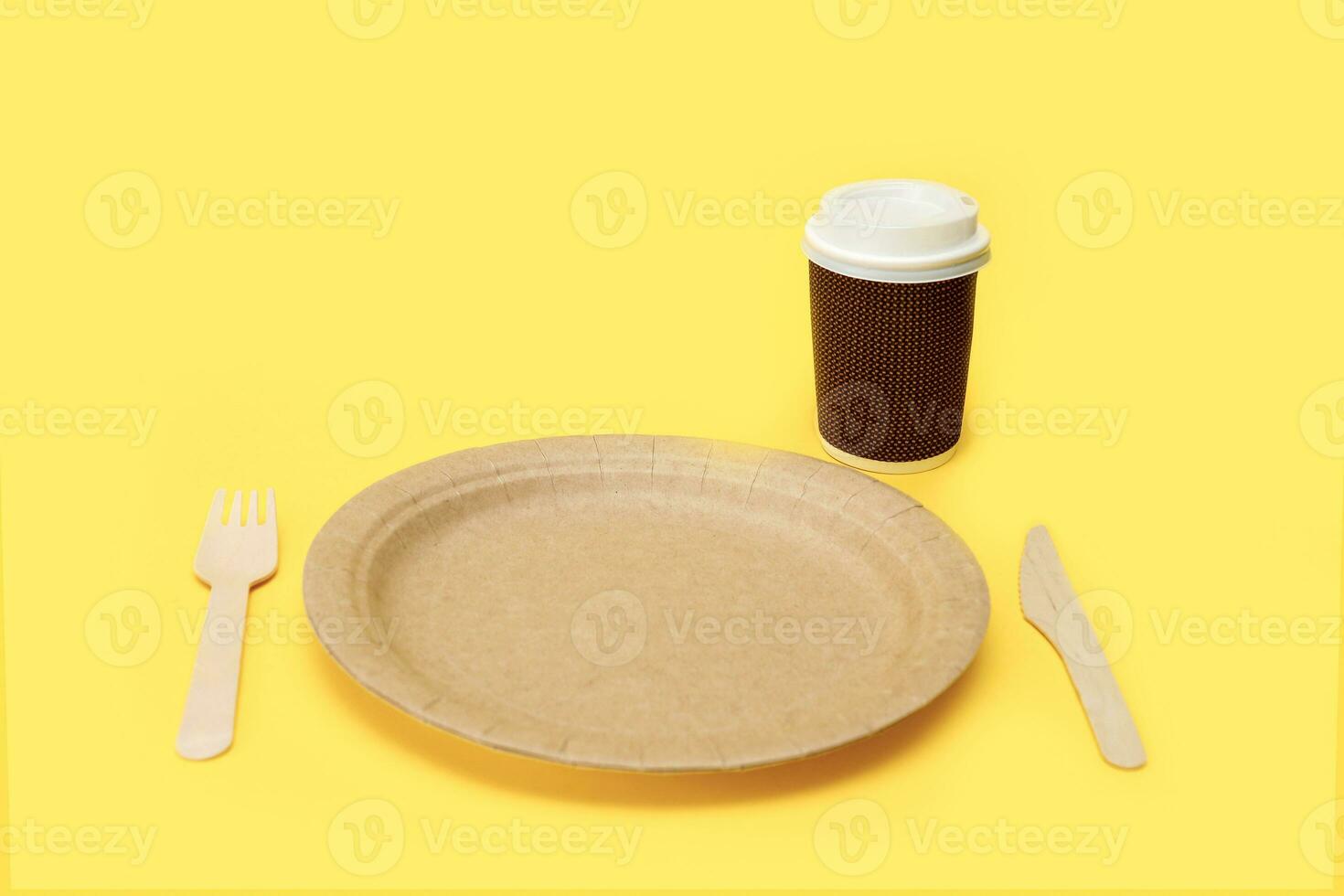 paper disposable plate with bamboo fork and knife and paper cup on yellow background photo