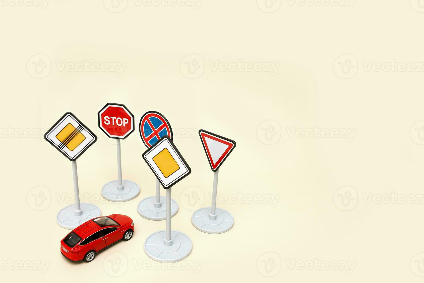 toy red car in front of many road signs on a light background with copy space photo