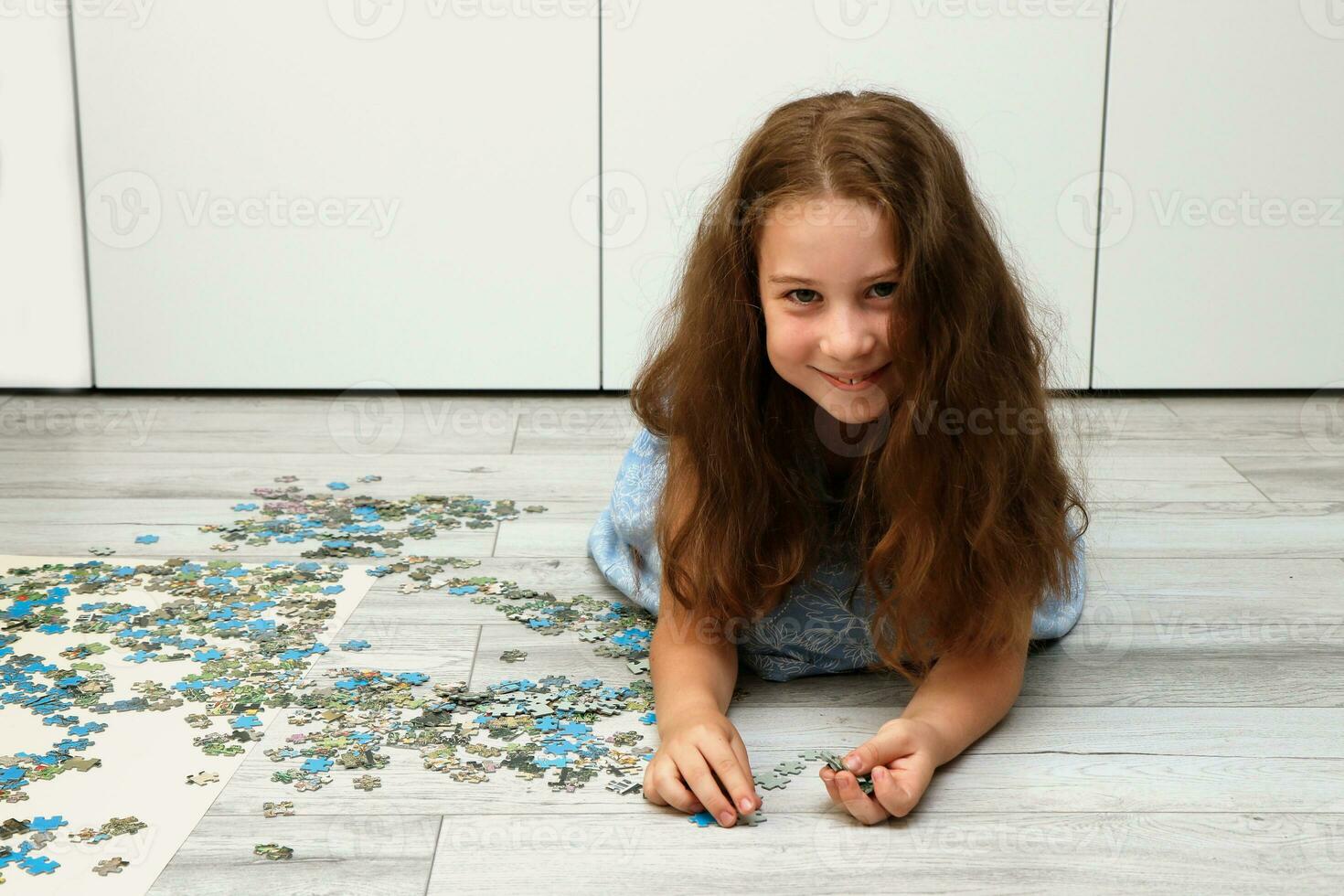 girl collects a puzzle from small pieces photo