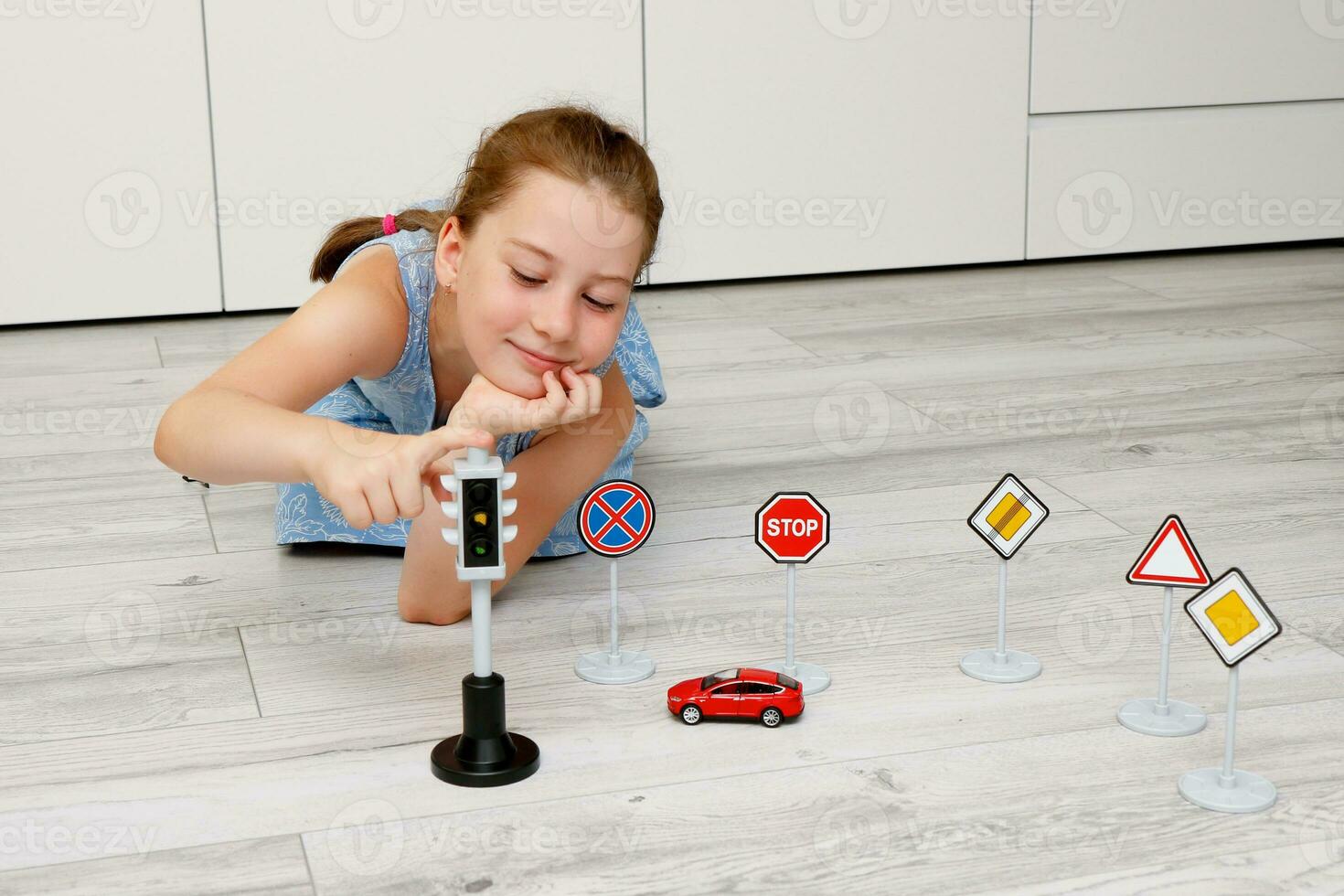 cute little girl playing at home on the floor with a road signs and traffic lights photo