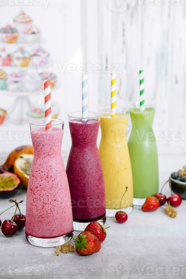 Four different smoothies of berry, banana with tangerine, kiwi, strawberries photo