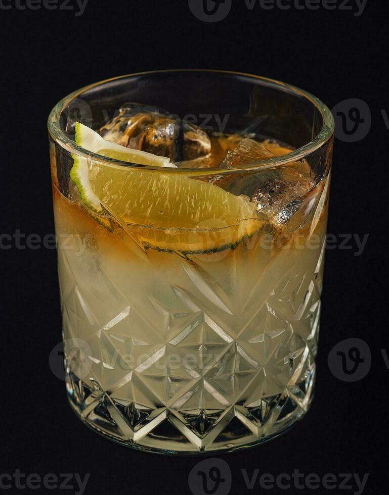 Yellow drink with lime on dark background photo