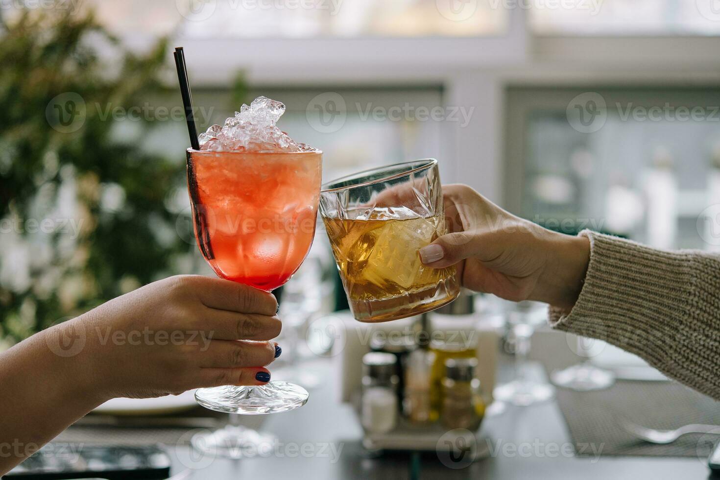 Friends toasting with glasses of whiskey and strawberry cocktail photo