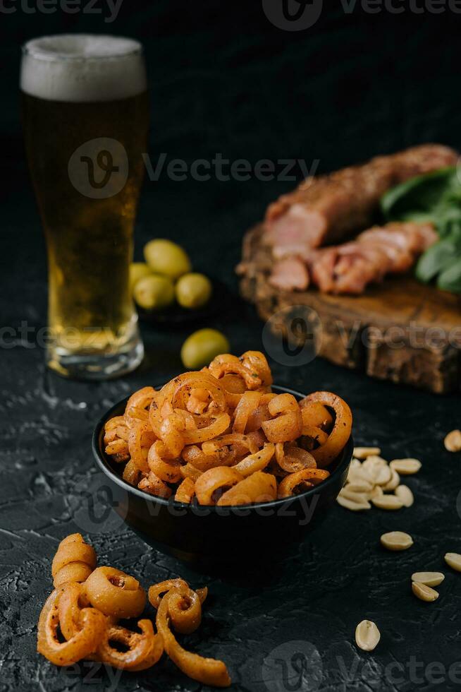 Pork ear snack in the bowl close up with beer in a glass photo