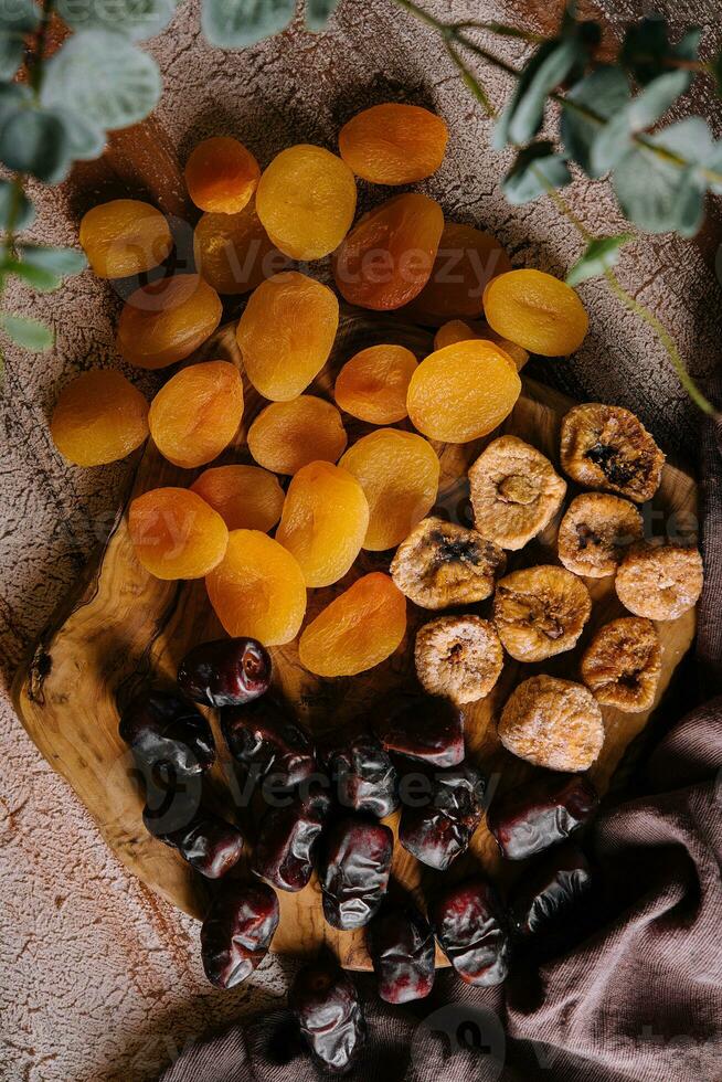 Different dried fruits on wooden background photo