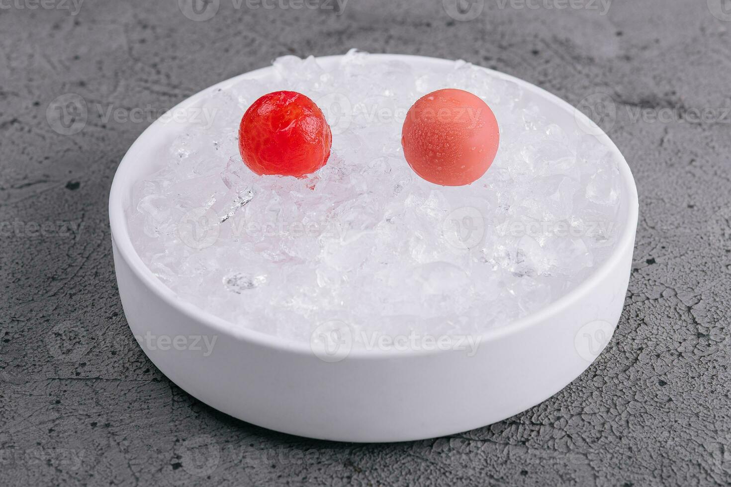 cherry tomatoes lie on ice in a white bowl photo