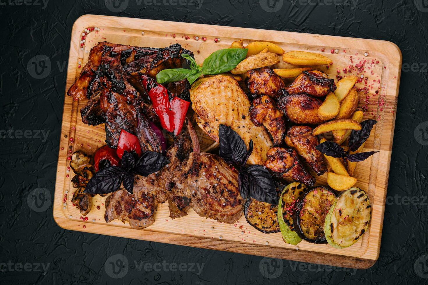 Mixed meat dish. grilled ribs, chicken wings, rack of lamb with vegetables photo