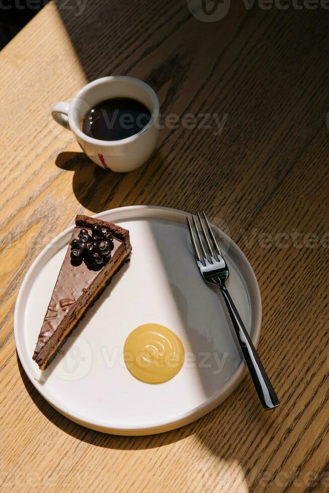 Chocolate cake with a coffee cup on wooden table photo