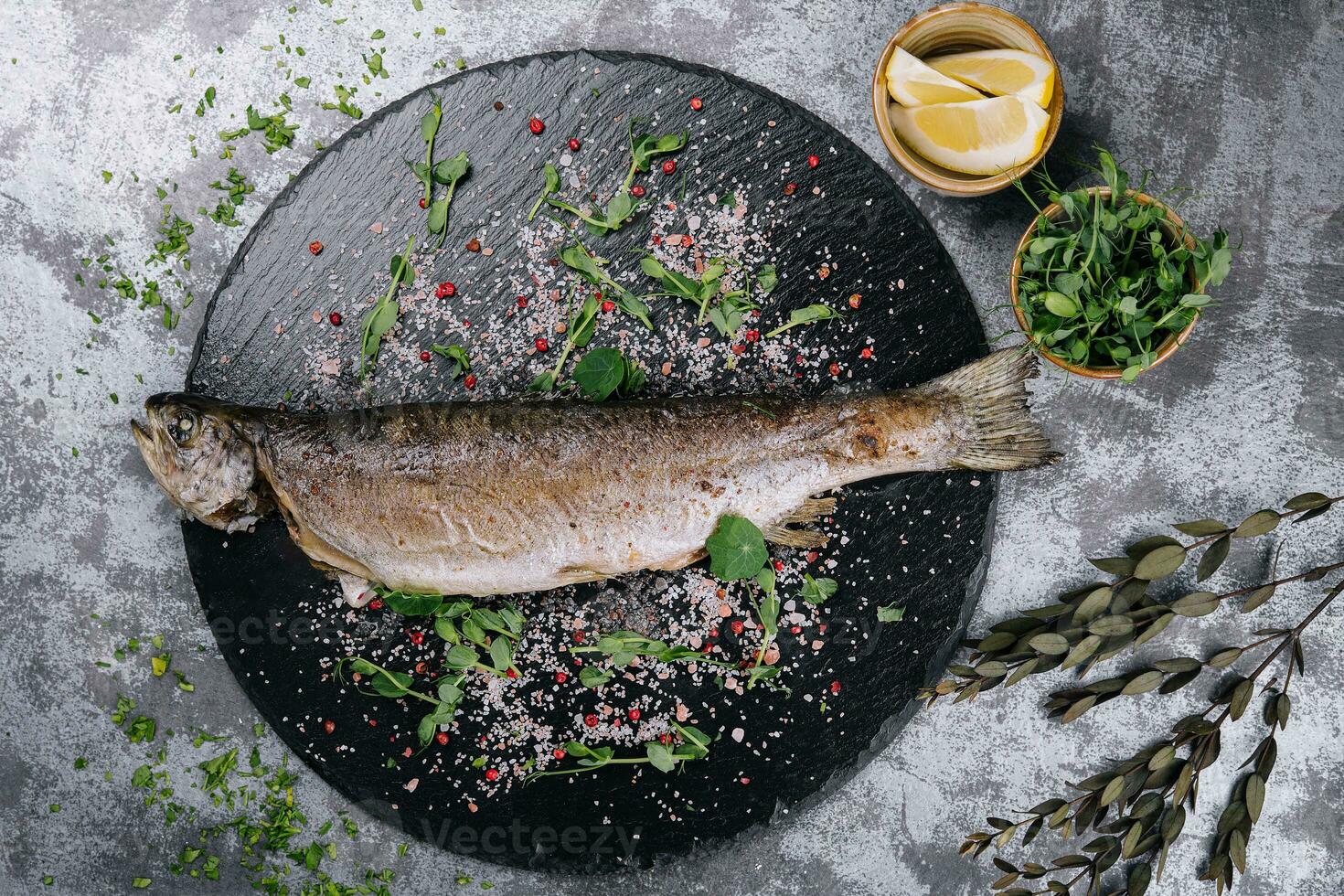 Grilled spicy fish on black plate, top view photo