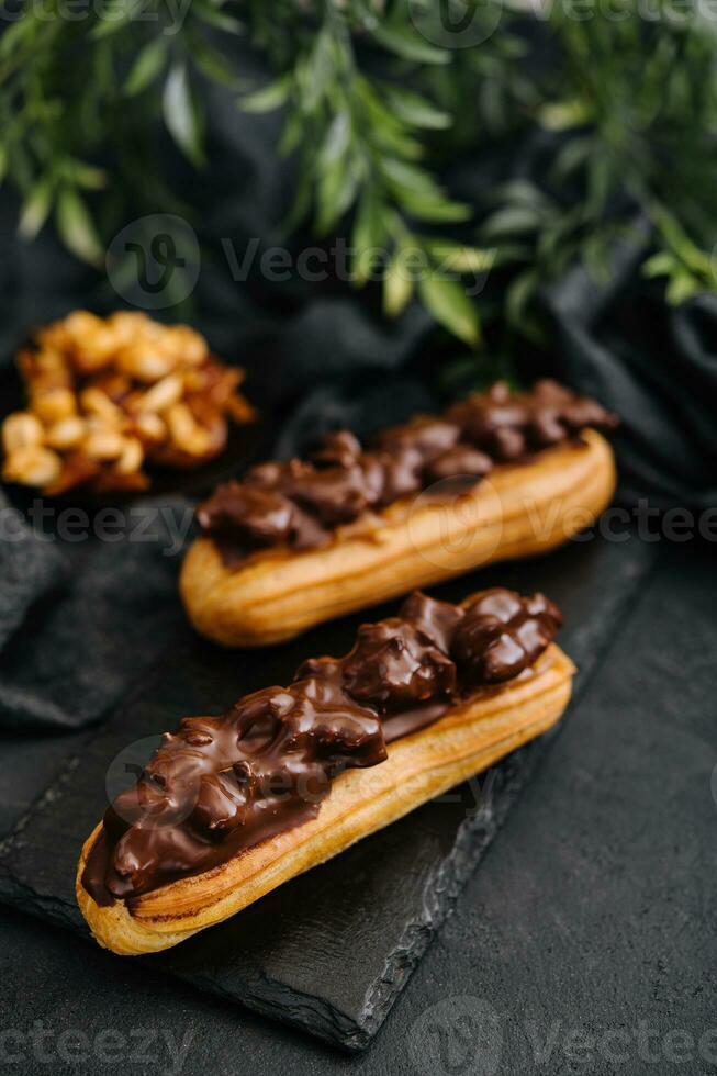 Two eclairs with dark chocolate on black board photo